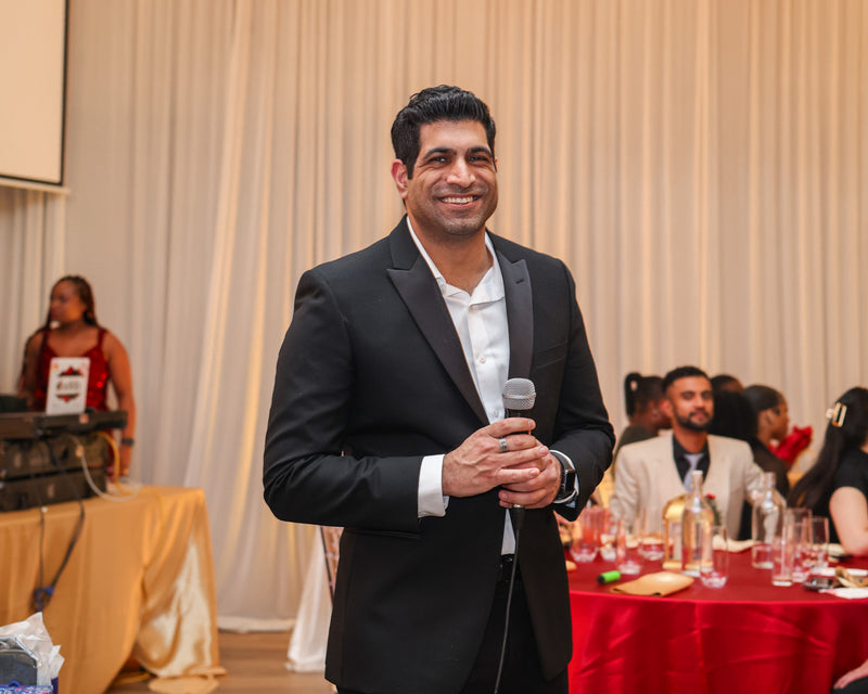Corporate event photography in Toronto capturing a speaker holding a microphone during a formal company banquet and networking event.
